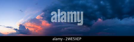Dramatic panorama of sunset sky with dark stormy clouds. Stock Photo