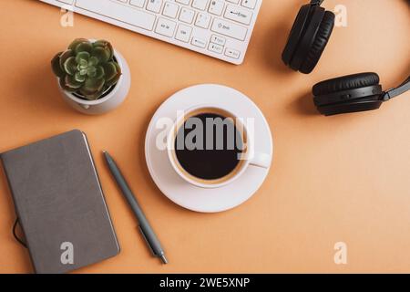 Desktop with coffee cup, notepad, keyboard, succulent plant and headphones on beige table. Top view, flat lay. Stock Photo