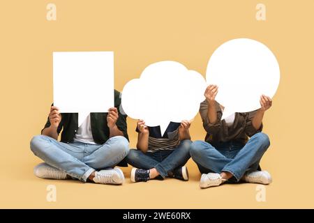 Black mom, dad and son hiding behind empty speech bubbles Stock Photo