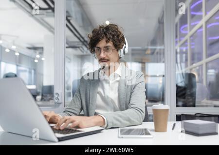Focused adult male office worker displaying professionalism while using laptop. Emotionally invested and experienced in business tasks. Stock Photo