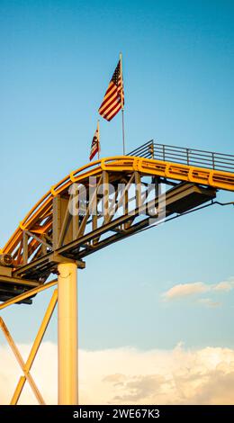 Yellow roller coaster track with an American flag and California flag at the peak Stock Photo