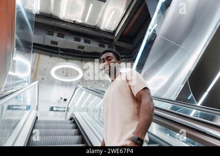 Young man standing on escalator at metro station using VR goggles Stock Photo