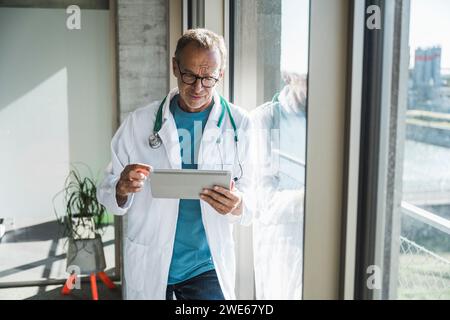 Senior doctor using tablet PC near window Stock Photo
