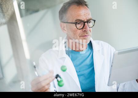 Senior man in lab coat using tablet PC Stock Photo