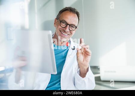 Happy senior man in lab coat holding tablet PC and molecular structure Stock Photo