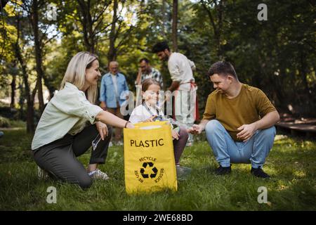 Socially inclusive group of volunteers putting plastic waste in recycling bag Stock Photo