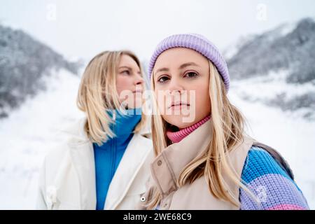 Blond woman wearing knit hat and standing with friend in winter Stock Photo