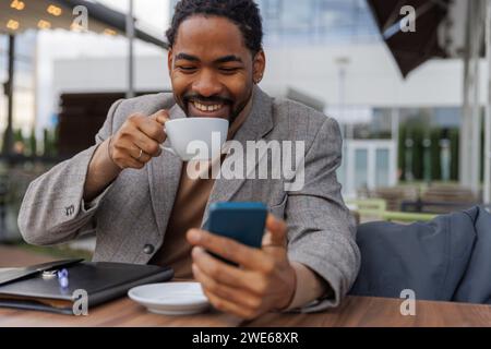 Happy businessman drinking coffee and using smart phone Stock Photo