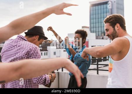 Happy friends dancing on rooftop Stock Photo
