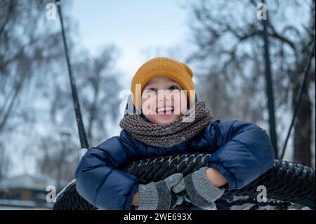 Playful boy swinging on nest swing in park Stock Photo