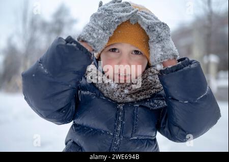 Boy touching yellow knit hat in winter Stock Photo