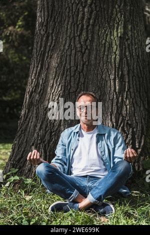 Senior man meditating in lotus position at park Stock Photo
