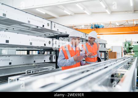 Engineers planning and having discussion near machinery in factory Stock Photo