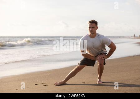 Young man doing stretching exercise at beach Stock Photo