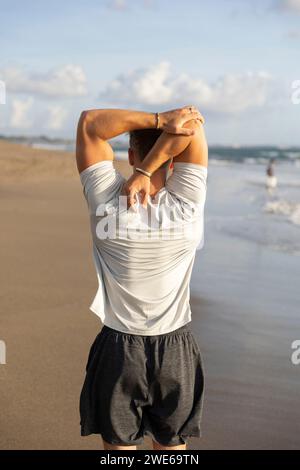 Man doing stretching exercise at beach Stock Photo