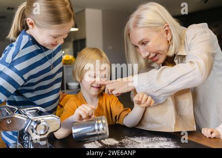 Happy grandmother touching nose of grandson at dining table Stock Photo