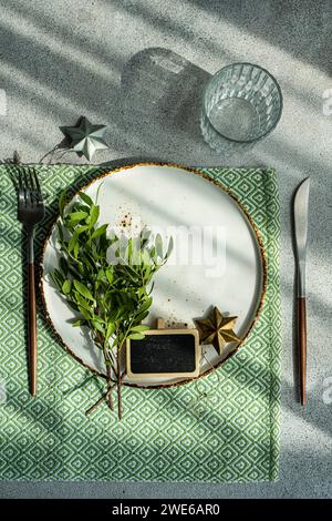 Dinner set with fresh pistachio tree branches as a festive decoration on concrete table background in sunny day Stock Photo