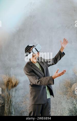 Young businessman wearing virtual reality simulator and gesturing in garden Stock Photo