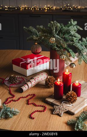 Red candles with gift box near decorated potted Christmas tree on table Stock Photo