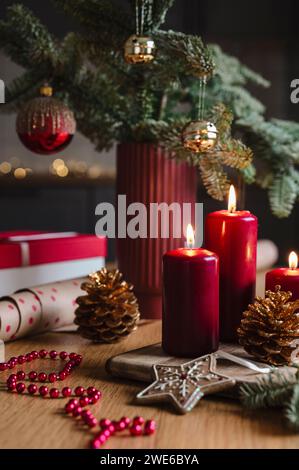 Red candles near potted Christmas tree with decoration on table Stock Photo