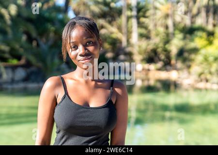 Smiling woman wearing black tank top at park on sunny day Stock Photo