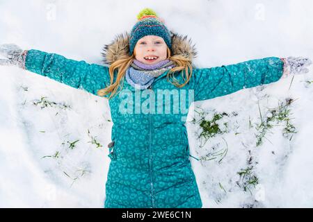 Playful girl wearing parka jacket and making snow angel Stock Photo