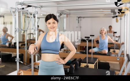 Portrait of woman in sportswear smiling at camera against group class in pilates fitness studio Stock Photo