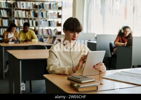 Young student using tablet PC at desk in library Stock Photo