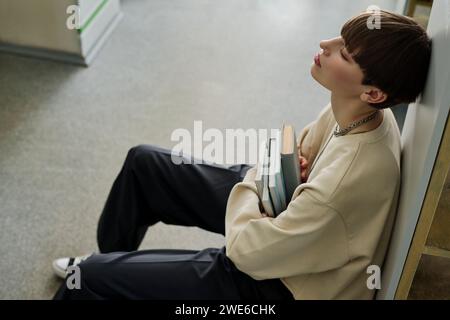 Tired student sitting with books in library Stock Photo