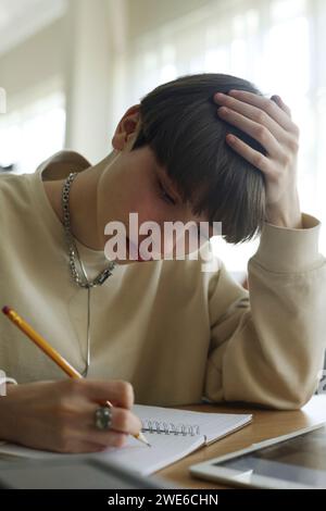 Student writing in book and studying at library Stock Photo