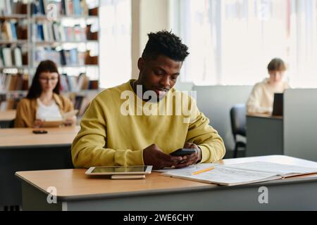 Young student using smart phone in library at university Stock Photo