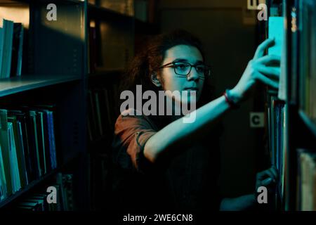 Student choosing book from shelf in library Stock Photo