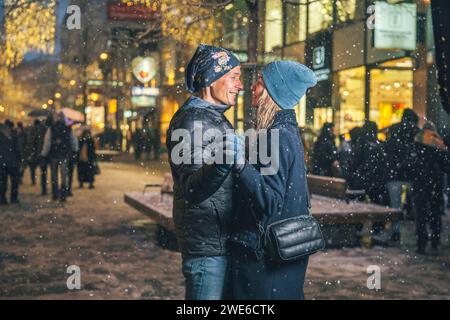 Happy loving couple dancing in snow at Christmas market Stock Photo
