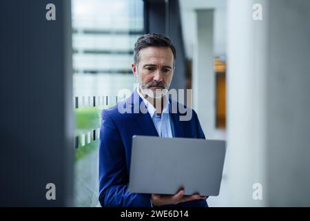 Businessman using laptop near glass window Stock Photo