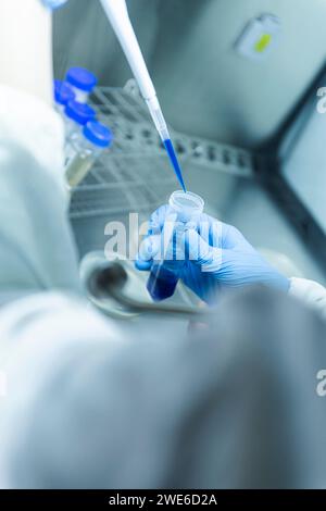 Scientist taking blue liquid sample in pipette from test tube at laboratory Stock Photo