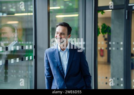 Smiling businessman standing near glass window Stock Photo