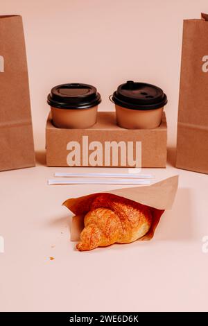 Croissant near coffee cups against beige background Stock Photo