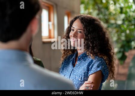 Smiling businesswoman discussing with colleagues in corridor Stock Photo