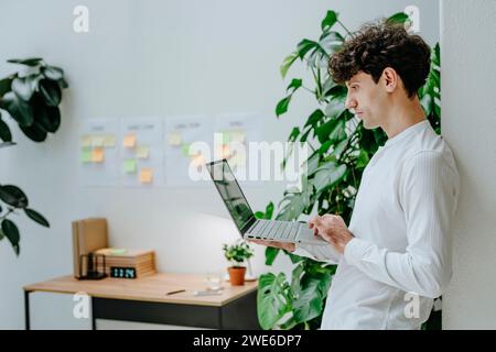 Businessman standing and using laptop in office Stock Photo