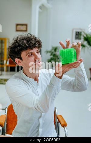 Businessman holding and examining cube shape maze in office Stock Photo