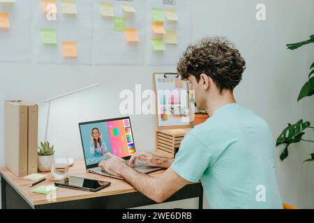 Web designer working on laptop at desk Stock Photo