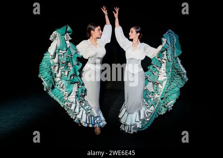 Young flamenco dancers dancing with hand raised against black background Stock Photo