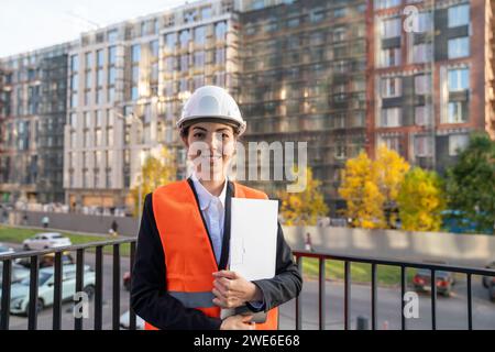 Smiling engineer holding file folder and standing in balcony Stock Photo