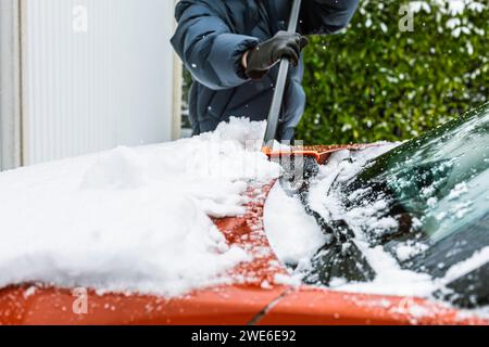 Cleaning snow from windshield. Cleaning and clearing the car from snow on a winter day. Stock Photo