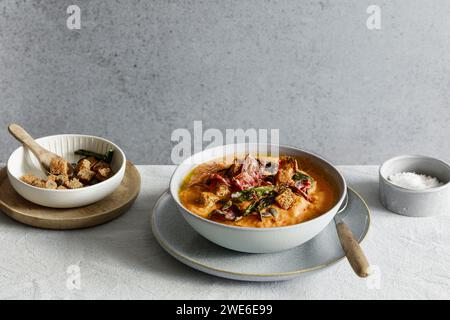 Studio shot of bowl of ready-to-eat pumpkin soup with croutons and beetroot chips Stock Photo