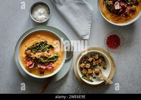 Studio shot of bowl of ready-to-eat pumpkin soup with croutons and beetroot chips Stock Photo