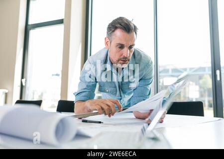 Architect leaning on desk and working with documents in office Stock Photo