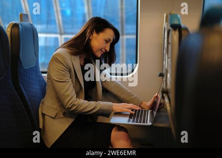 Mature businesswoman working on laptop in train Stock Photo