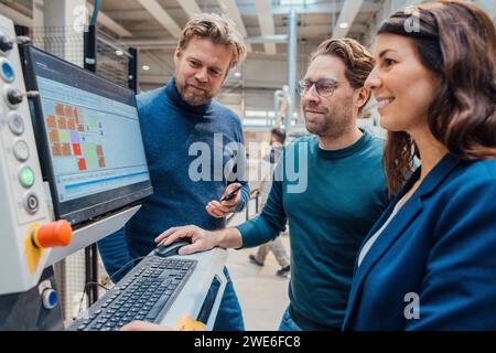 Smiling business colleagues working on computer in workshop Stock Photo