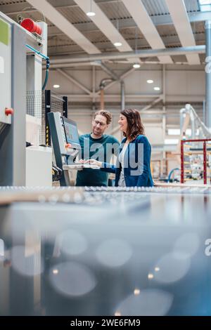 Colleagues discussing over computer standing in industry Stock Photo